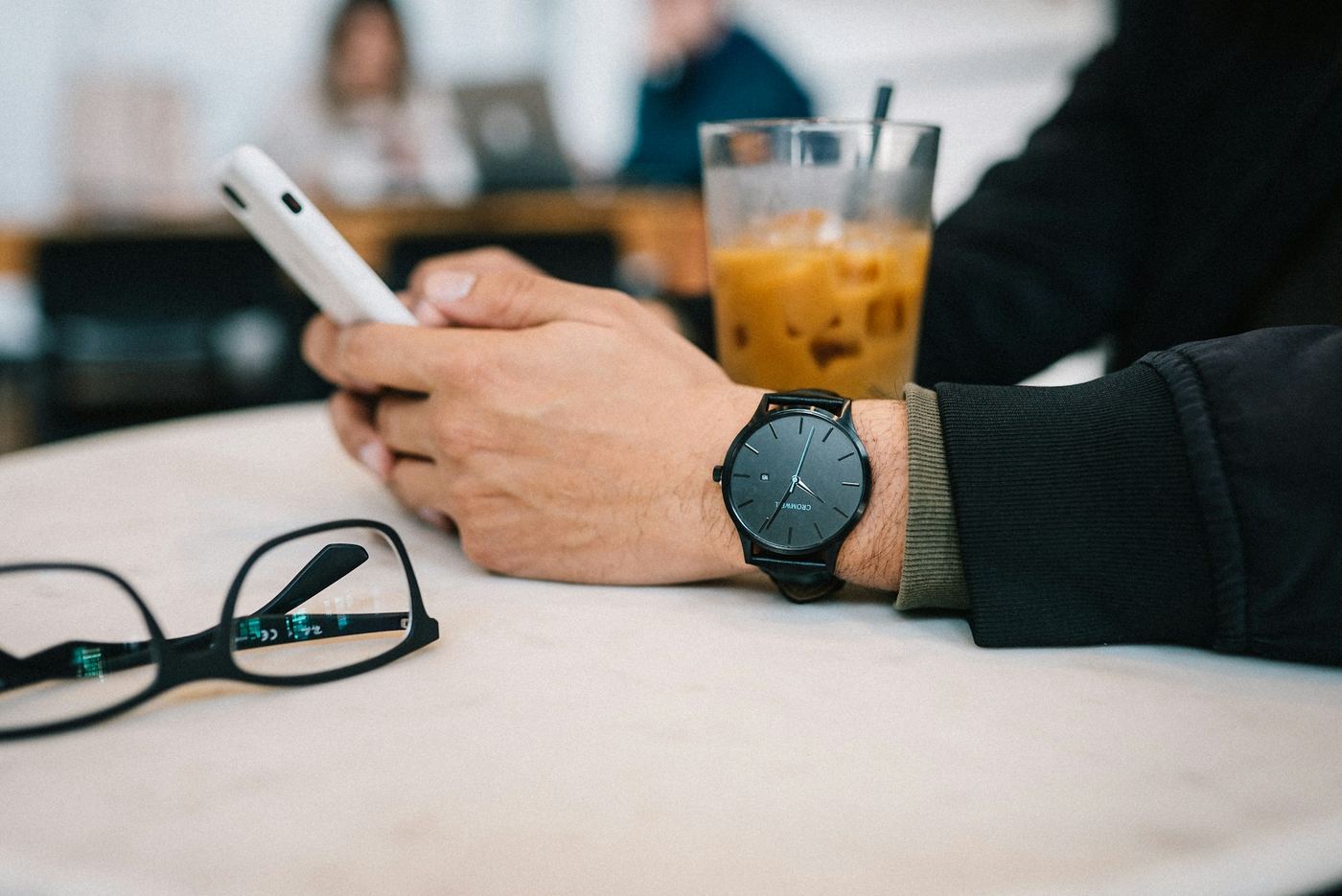 Cliente escribiendo en su móvil en la mesa de un café